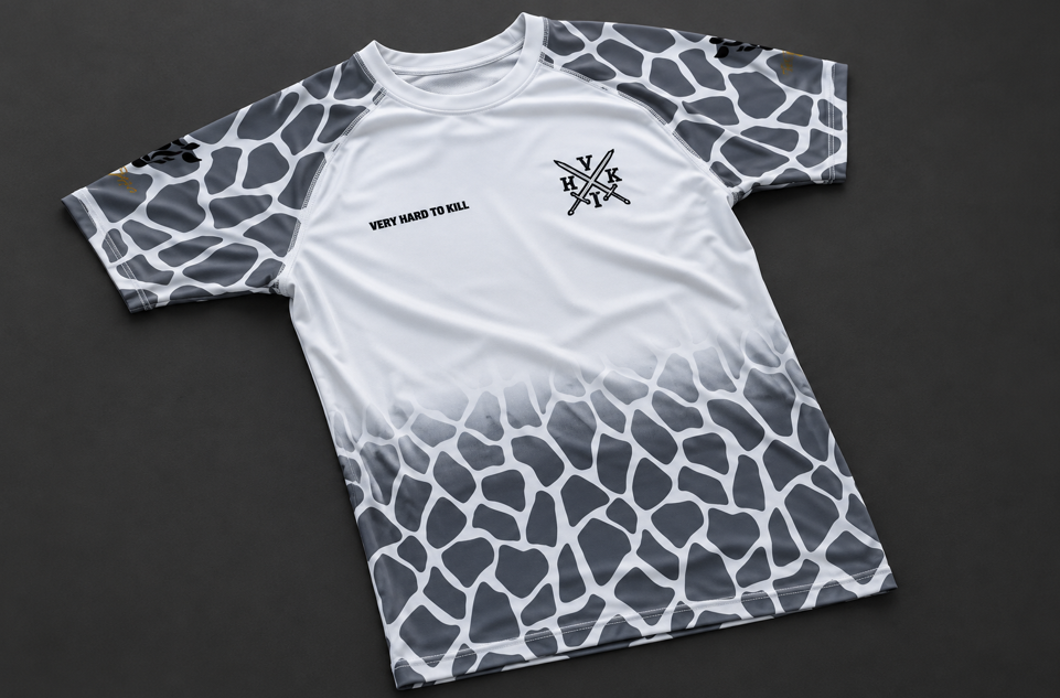 Front view of VHTK All White Giraffe rash guard with grey giraffe patterns and black chest branding on a charcoal background.
