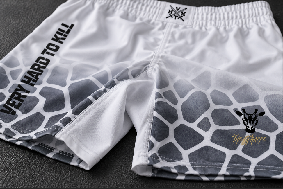Close-up of VHTK All White Giraffe shorts showing the inner thigh seam, white stitching and gray giraffe artwork on a dark mat.