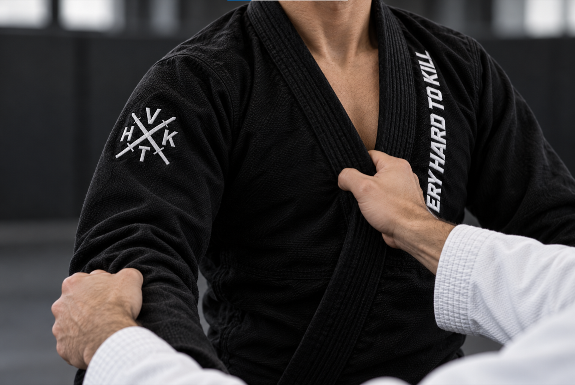 Partner gripping a black VHTK BJJ gi’s right sleeve and lapel, with the embroidered sleeve emblem visible.