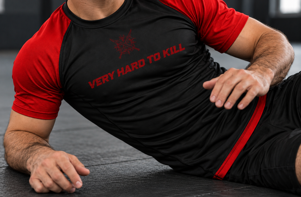 Athlete wearing VHTK Black Rankings Edition rash guard during a ground drill, showing red sleeves and a close torso fit.